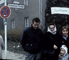 An East German family with a welcome sign in the background.