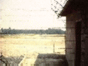 view through barbed wire fence to area where barracks once stood